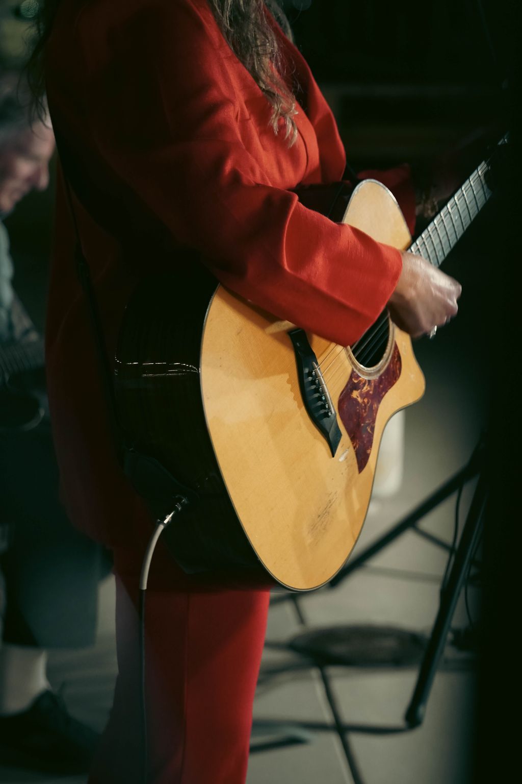 Nghệ sĩ đang hát và chơi guitar trên sân khấu nhỏ với ánh sáng ấm
