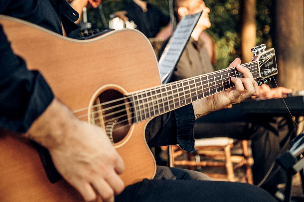 Bàn tay đang chơi guitar acoustic với ánh sáng nhẹ