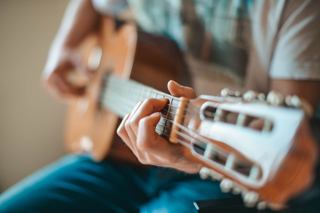 Nghệ sĩ đang chơi guitar acoustic trong không gian quán nhỏ ấm cúng